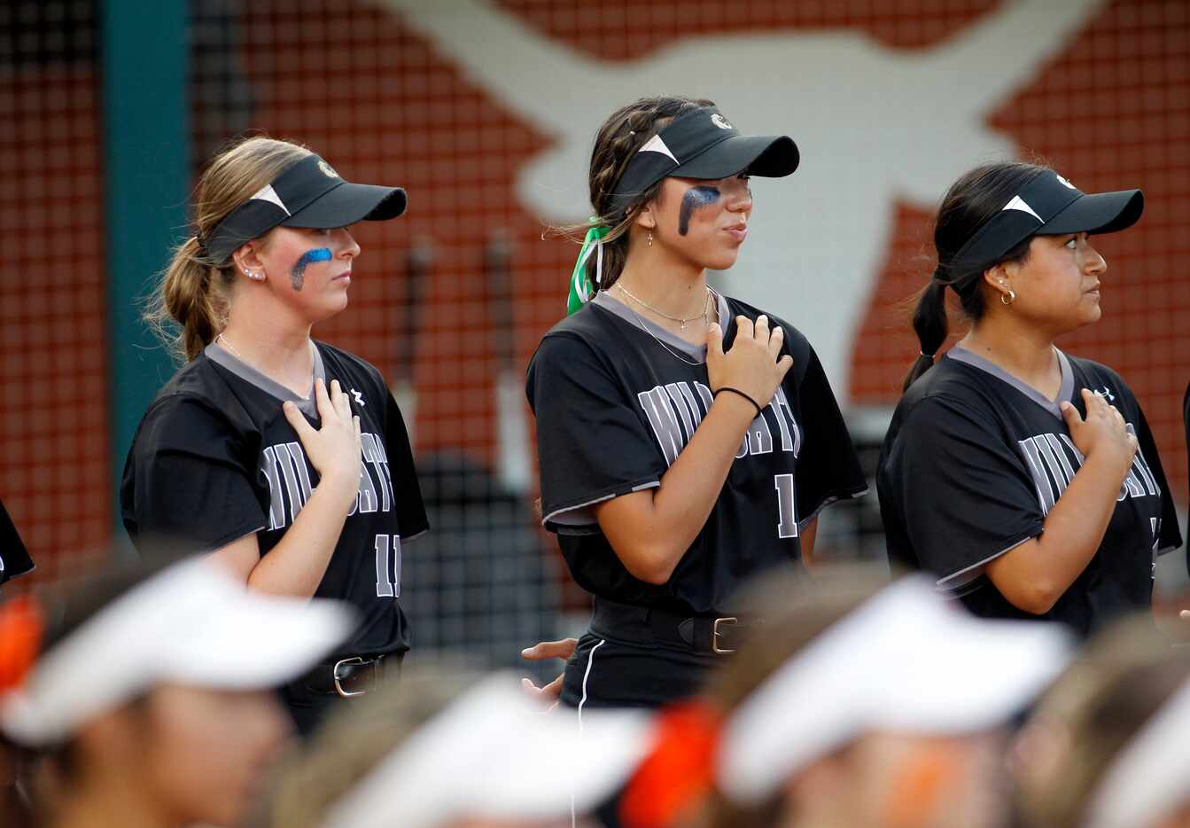Denton Guyer players pause for the playing of the national anthem prior to the start of...