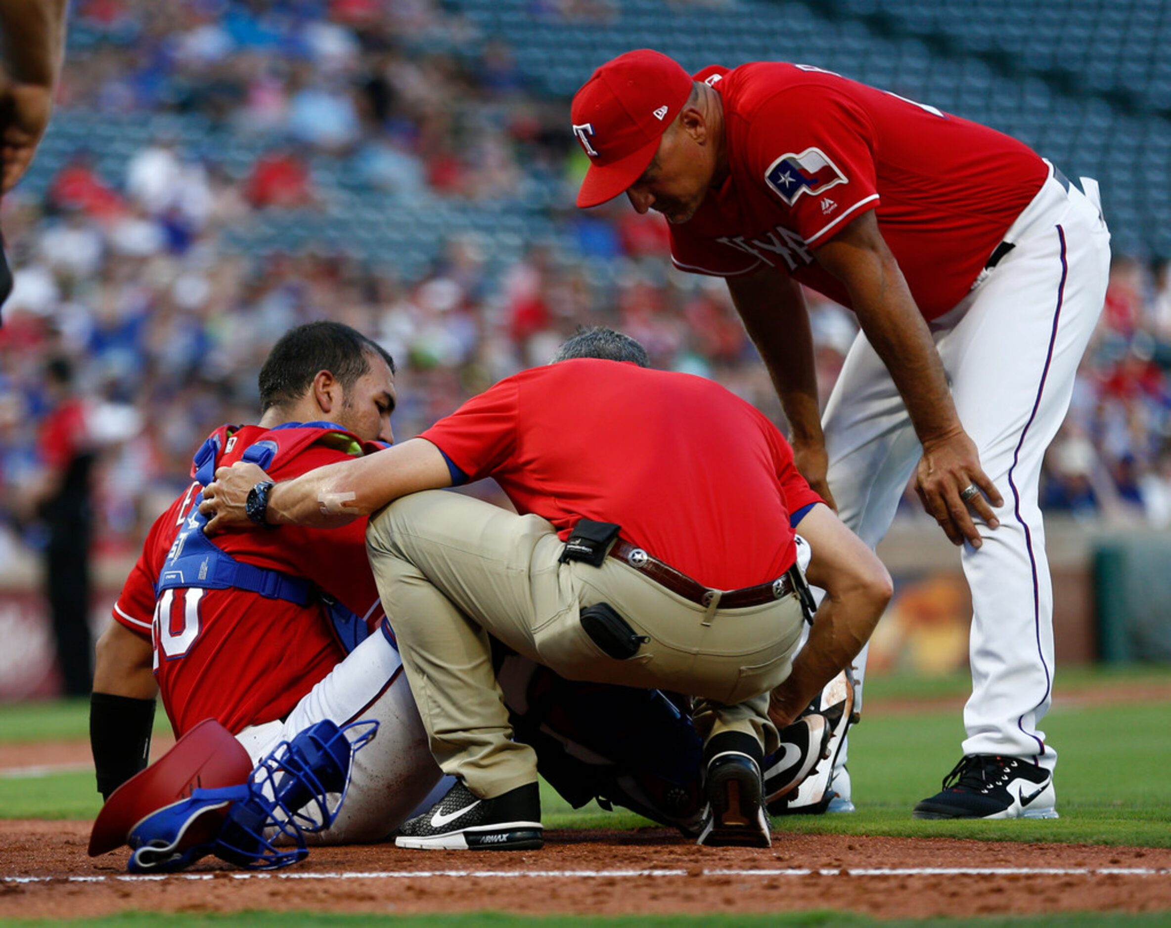 Texas Rangers catcher Carlos Perez, left, is checked by team trainer Kevin Harmon and...