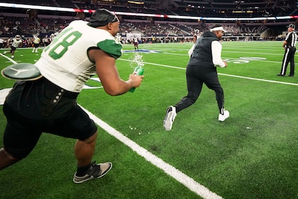 DeSoto defensive lineman Jason Douglas (48) chases head coach Claude Mathis with a bottle of...