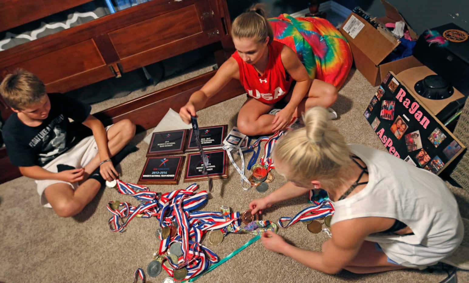 Gymnast Ragan Smith, center, goes through a box of medals, plaques and trophies with the...