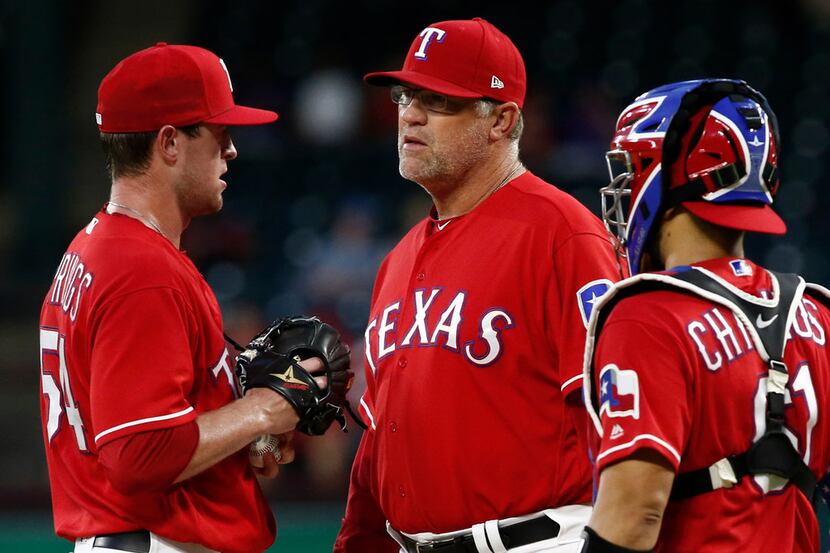 Texas Rangers starting pitcher Jeffrey Springs is checked by pitching coach Doug Brocail and...
