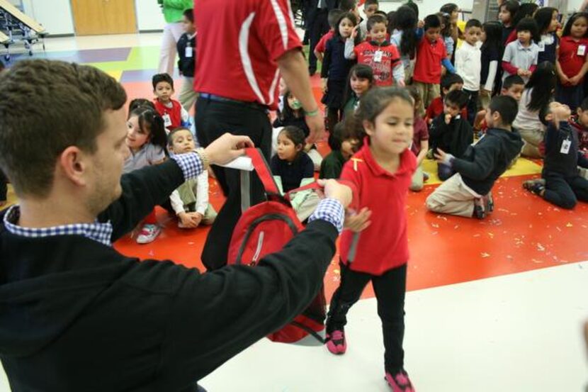 
#40AOK founder Beaux Wellborn helps a kindergarten student put on her new backpack during...