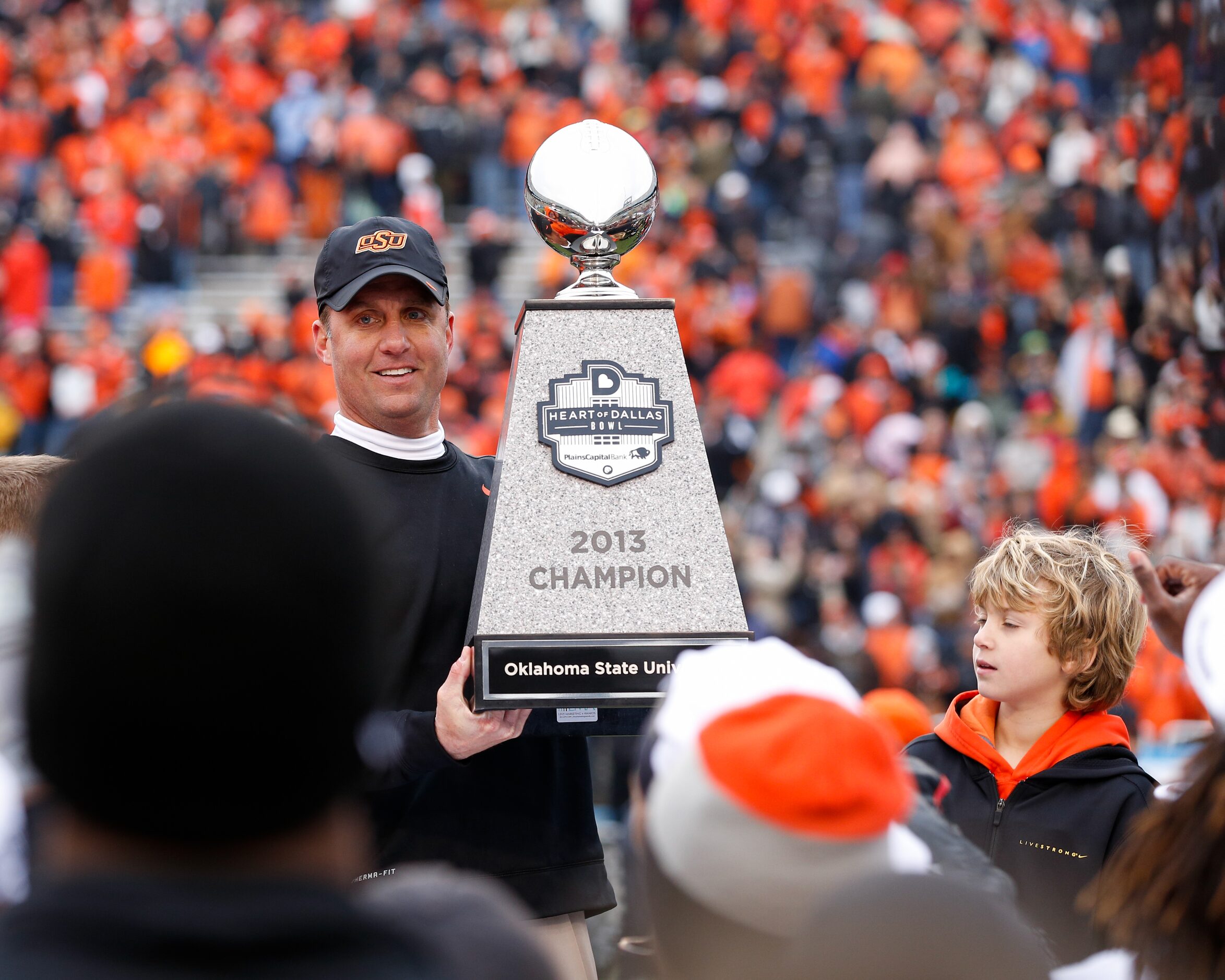 Oklahoma State's head coach Mike Gundy holds up the trophy after beating Purdue, 58-14,...