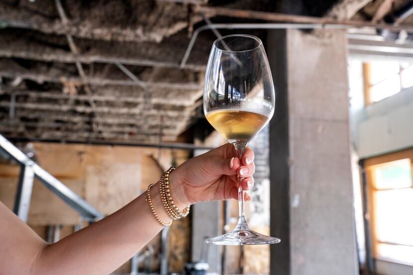 Amanda DeWitt displays a glass of wine inside the unfinished Preston Center space where she,...