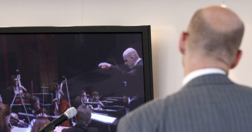 Emmanuel Villaume watches a video clip of himself conducting during Tuesday's news conference.