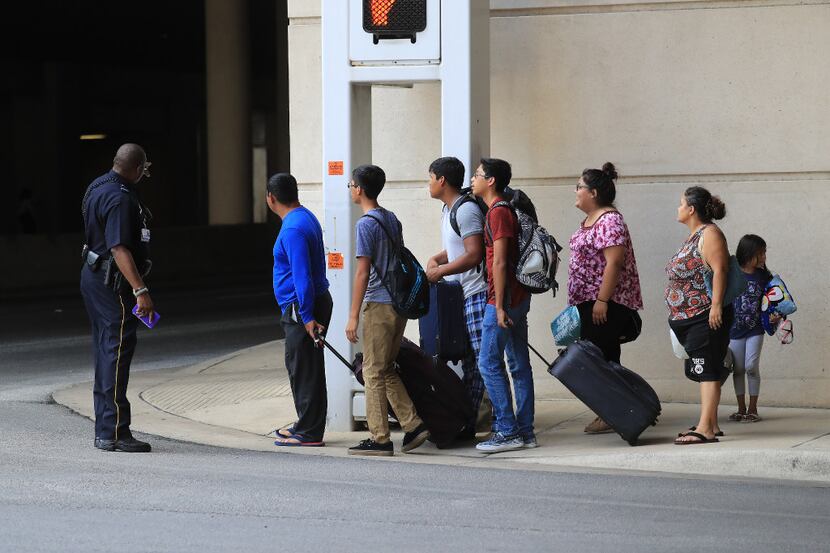 A police officer directed a group of evacuees from Houston to the entrance of the Kay Bailey...