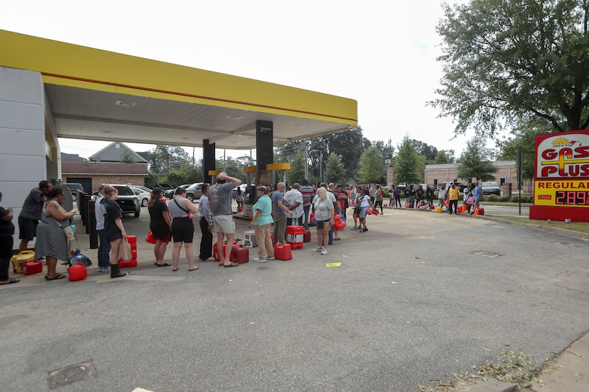 Residents wait in line with gas cans at a Gas Plus gas station in the aftermath of Hurricane...