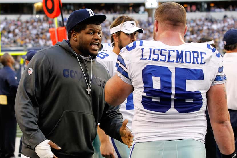 Dallas Cowboys player Josh Brent talks with teammate Sean Lissemore #95 as the Cowboys take...