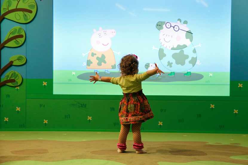 Standing on a carpet made to look like muddy puddles, Peyton Frazer, 2, of Highland Village,...