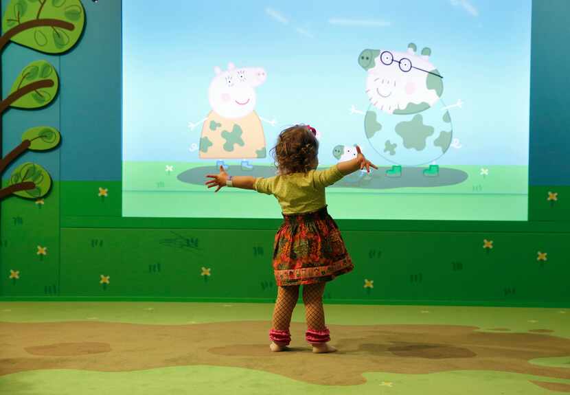 Standing on a carpet made to look like muddy puddles, Peyton Frazer, 2, of Highland Village,...