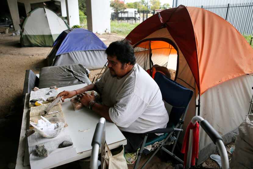 Jose Sanchez read recently while sitting outside his tent next to many others under an...