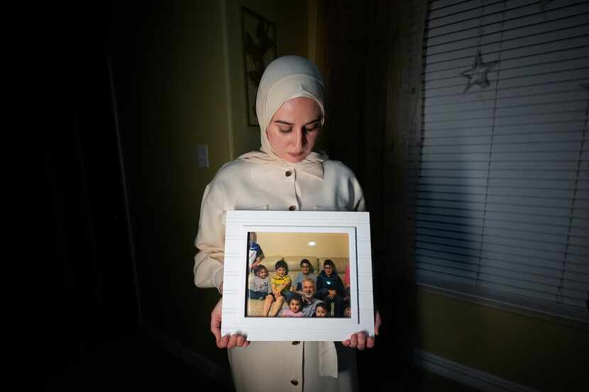 FILE - Maryam Kamalmaz hold a photo of her father with some of his 14 grandchildren in Grand...