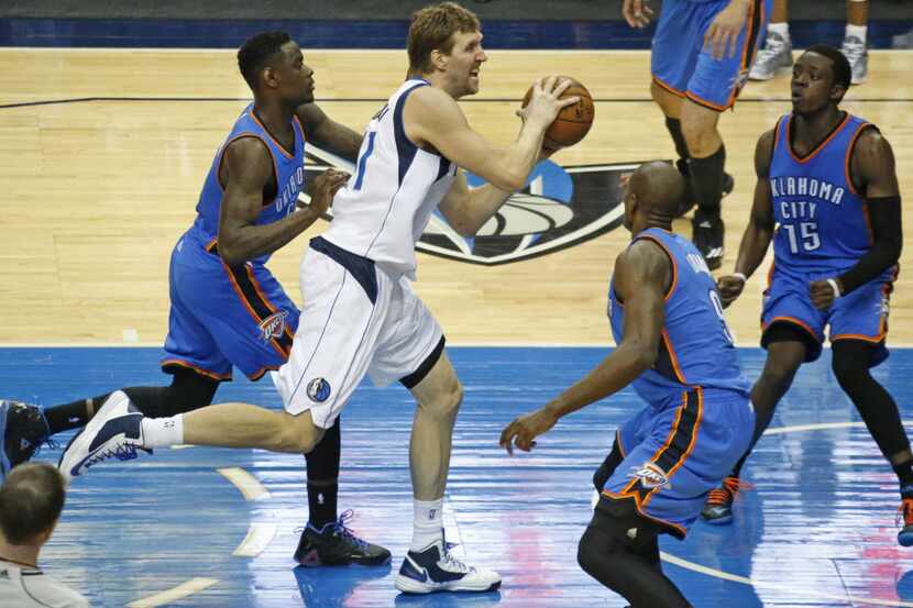 Dallas' Dirk Nowitzki drives the lane between three Oklahoma City emenders in the fourth...