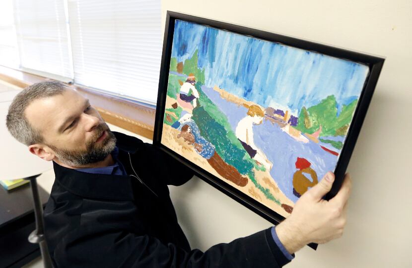 Brian Belcher, with Looney and Associates, hangs a student's artwork in a nearly decorated...