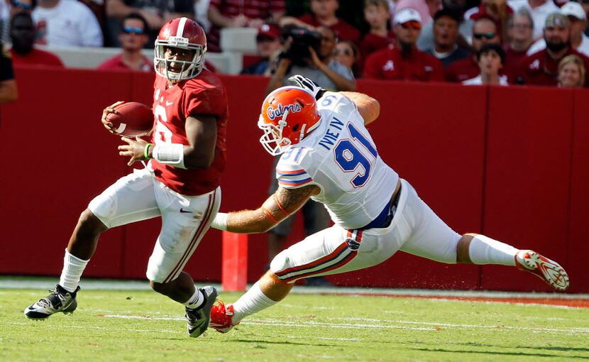 Alabama quarterback Blake Sims, left, scrambles for yardage around Florida defensive lineman...