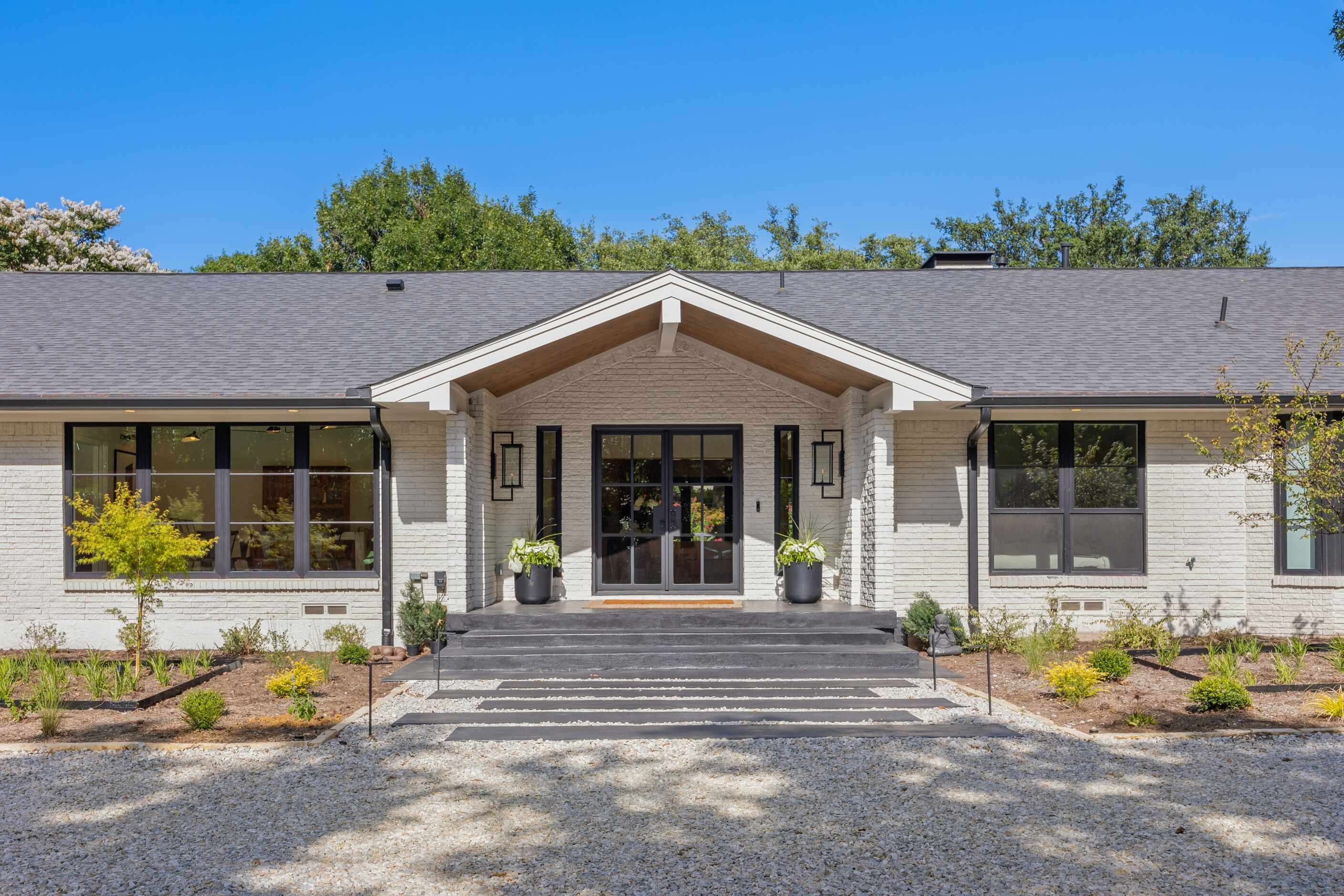 White midcentury modern house with gravel pathway and stone leading to front door