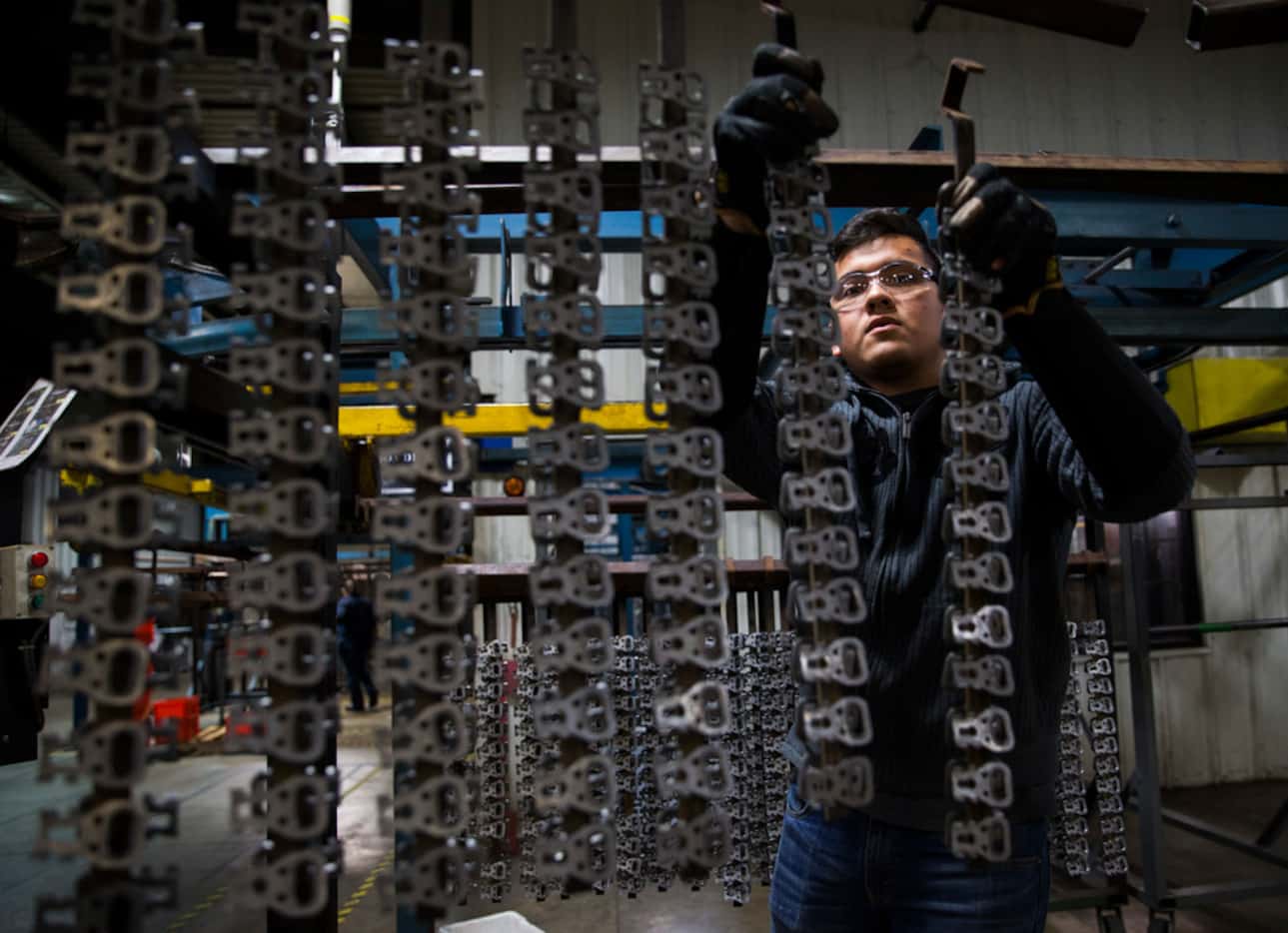 Jehu Salas hangs seatbelt parts that were manufactured inside the ITD Precision factory in...