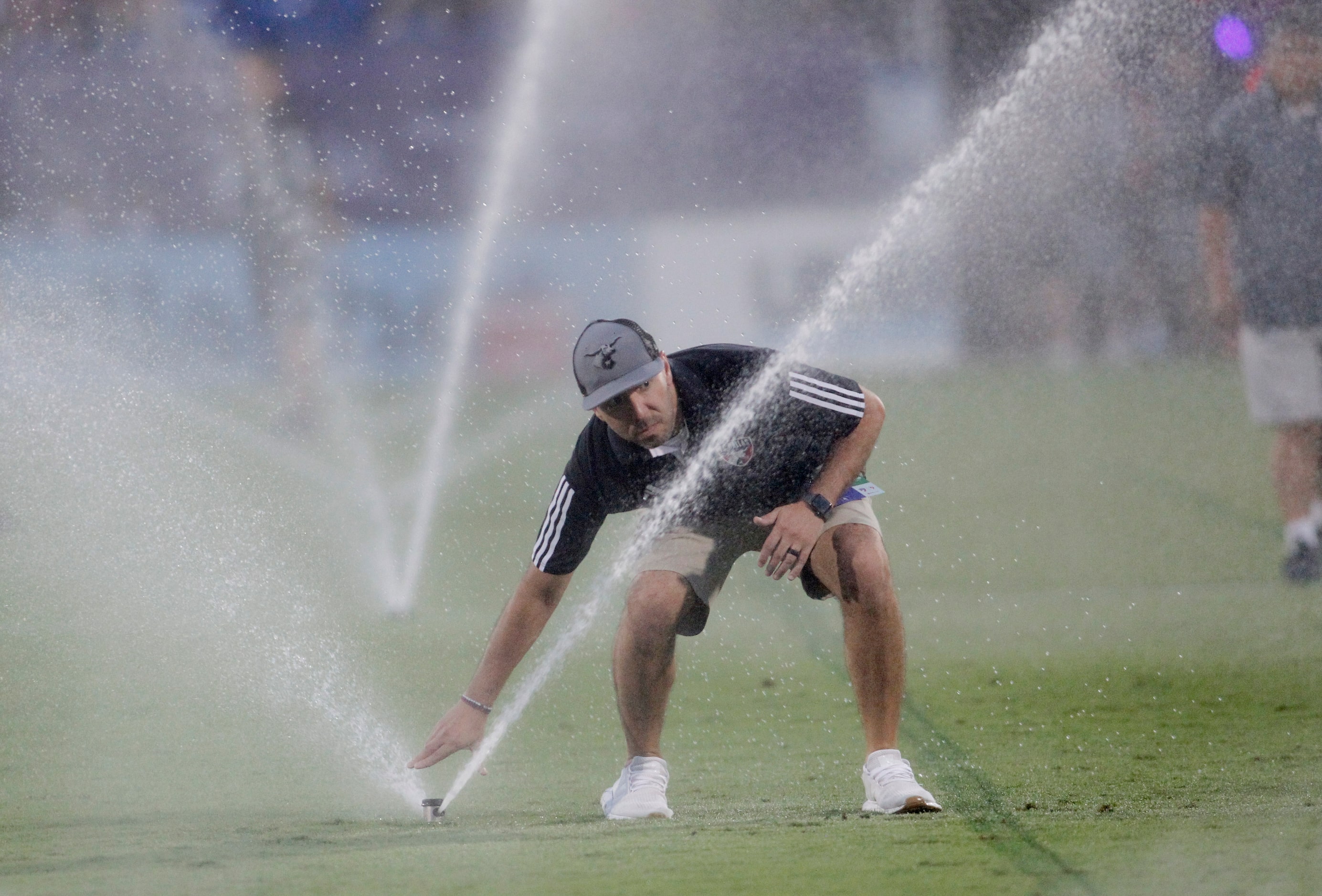 One of the groundskeepers adjusts the water spray onto the playing field prior to the start...