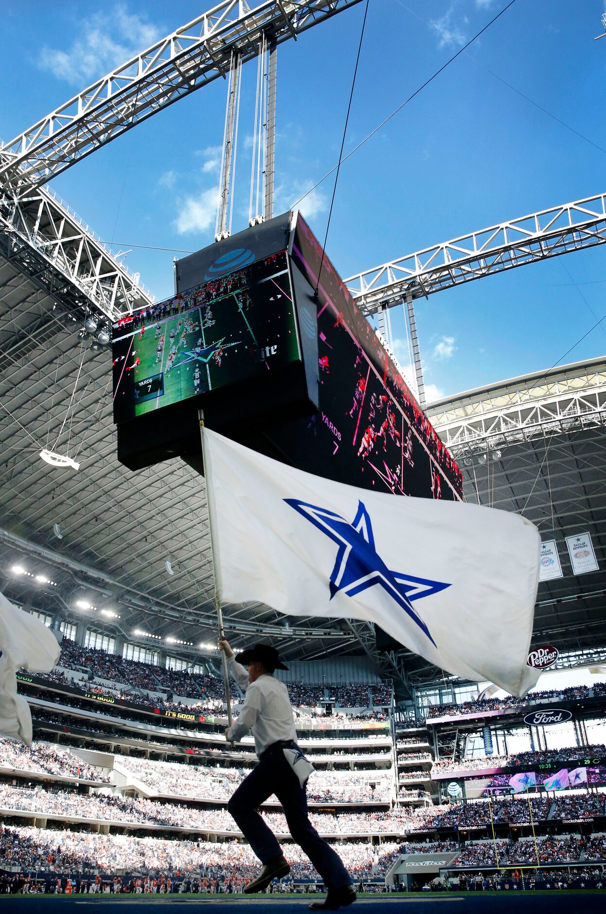 A member of the Dallas Cowboys flag team races across themed zone under an open roof during...