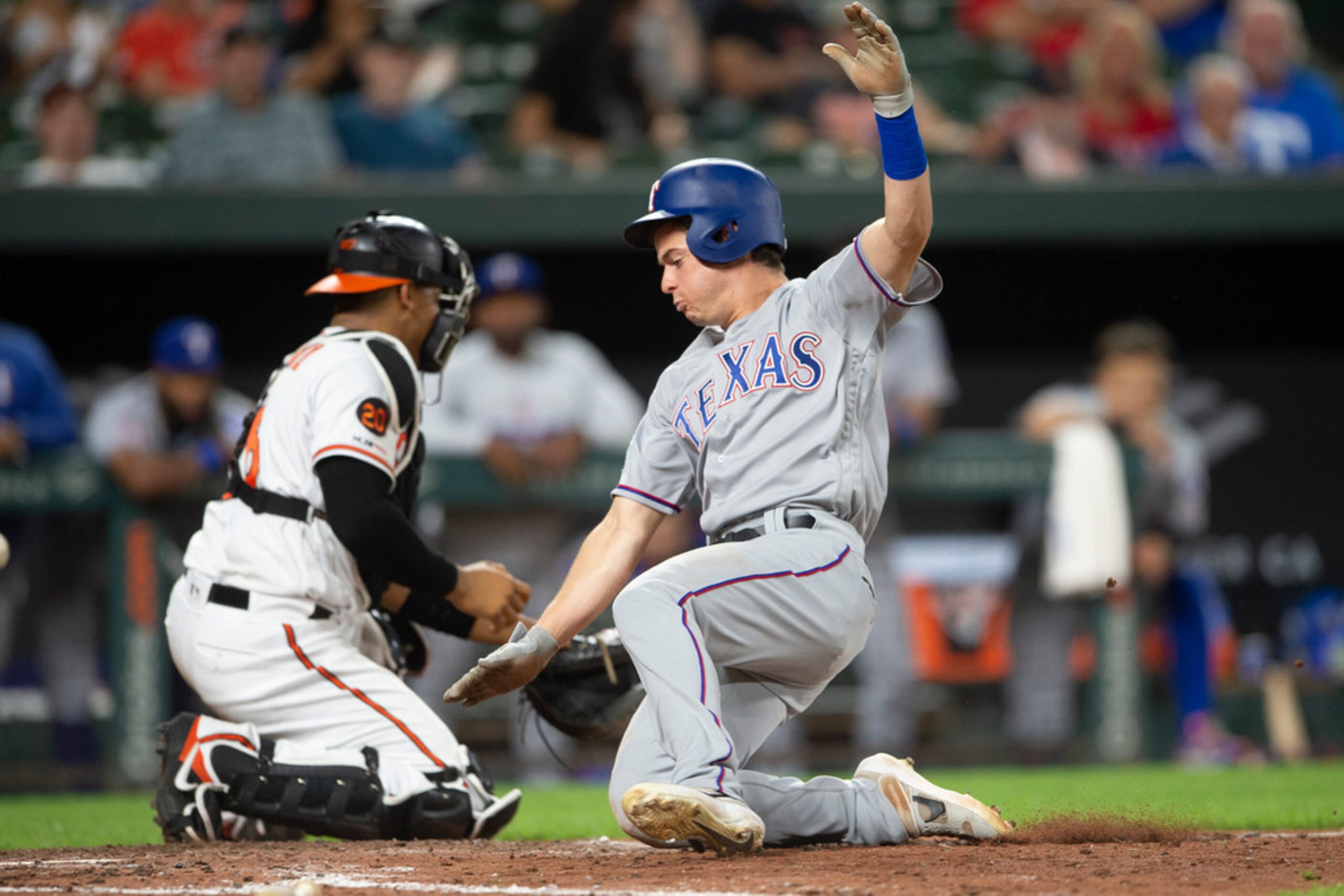 Texas Rangers' Nick Solak slides past Baltimore Orioles catcher Pedro Severino to score...