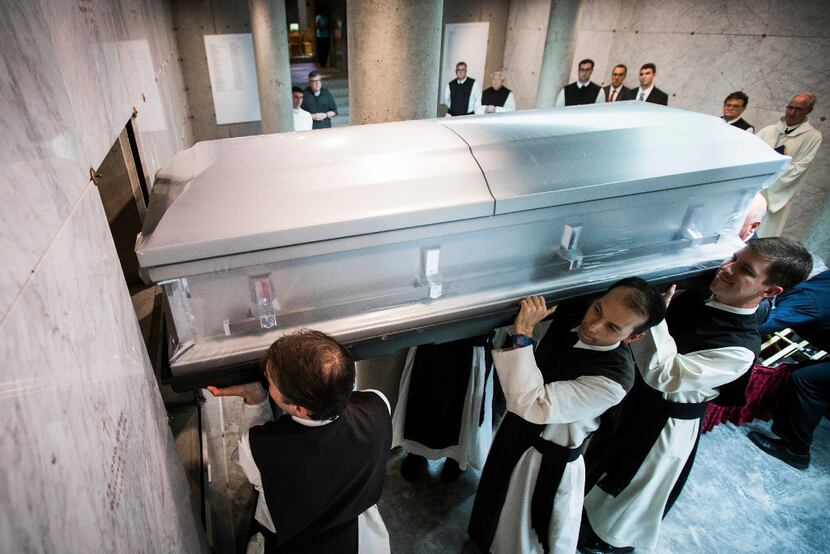 The remains of Rev. Rudolph Zimanyi are lifted into crypt by monks at the Cistercian Abbey...