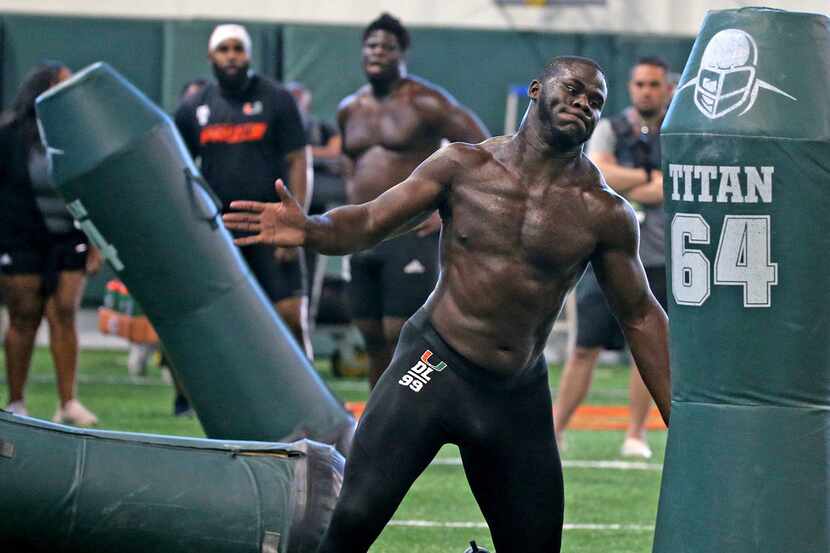 Miami defensive end Joe Jackson slaps the tackling dummies as he runs a drill at the NCAA...