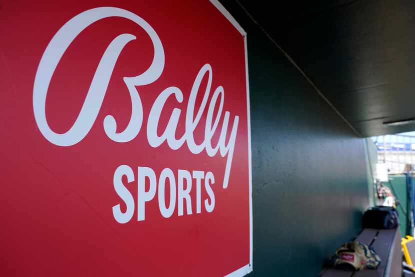 FILE - A Bally Sports logo is on a dugout wall during a spring training baseball game at...