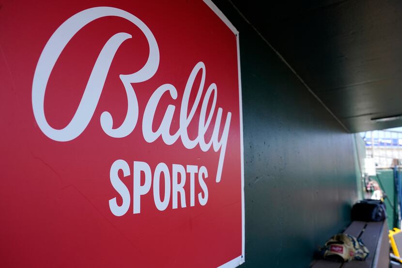 FILE - A Bally Sports logo is on a dugout wall during a spring training baseball game at...