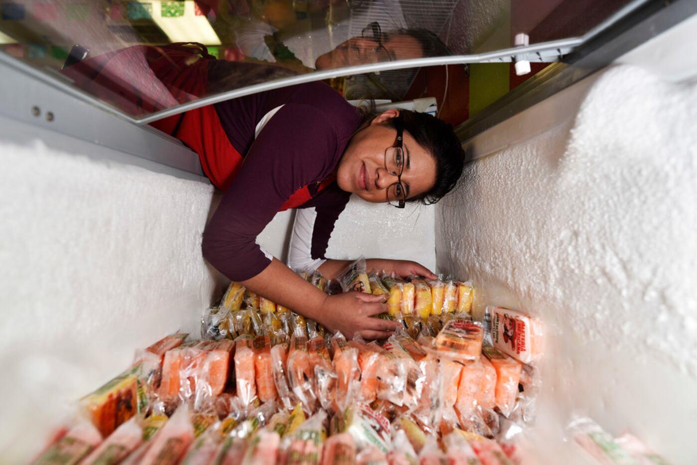 Marymar Nuñez, 19, leans into a freezer at La China Poblana snack and ice cream store along...
