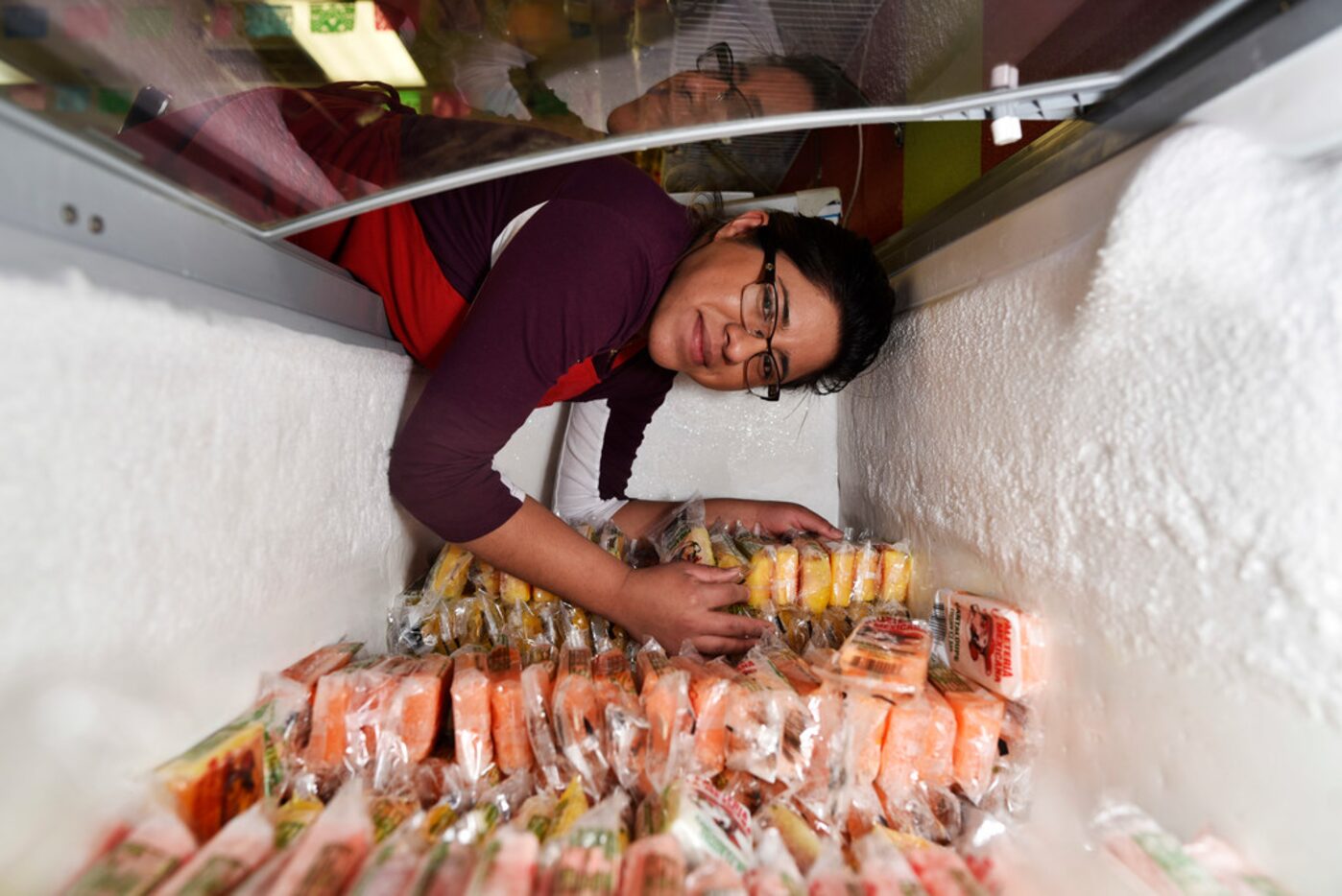 Marymar Nuñez, 19, leans into a freezer at La China Poblana snack and ice cream store along...