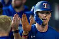 Texas Rangers left fielder Evan Carter celebrates with teammates after scoring against the...