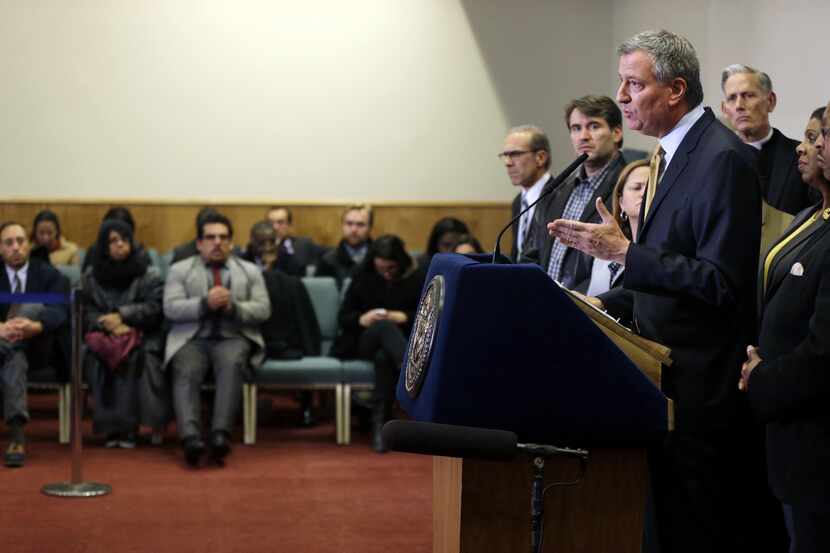 New York City Mayor Bill de Blasio, surrounded by community leaders, speaks to reporters...