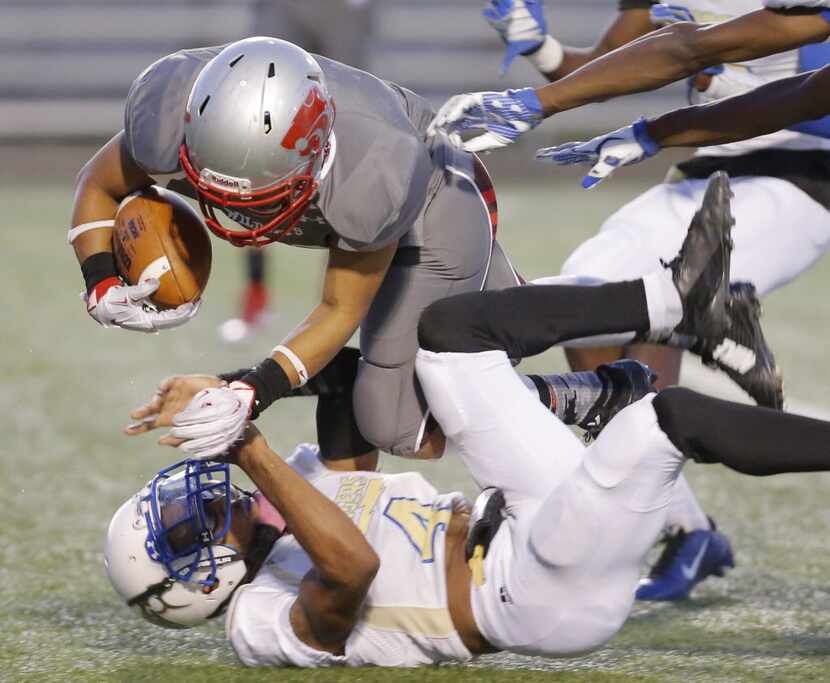 TXHSFB Woodrow Wilson senior running back Paul Clayborn (20) battles past Conrad senior...