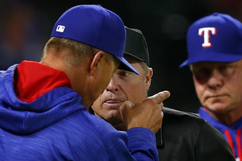 Texas Rangers manager Jeff Banister (left) has words with home plate umpire Marvin Hudson...