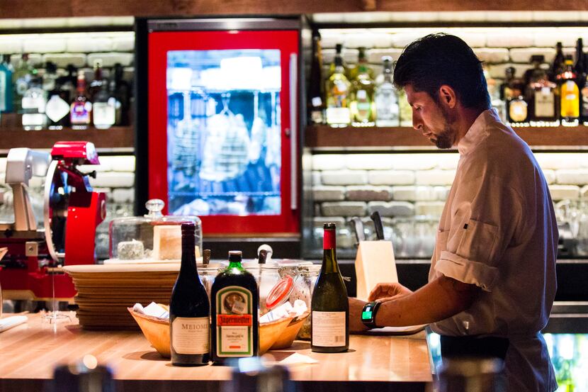 Chef Jonathan Melendez prepares appetizers at a prep island inside the bar at Paul Martin's...