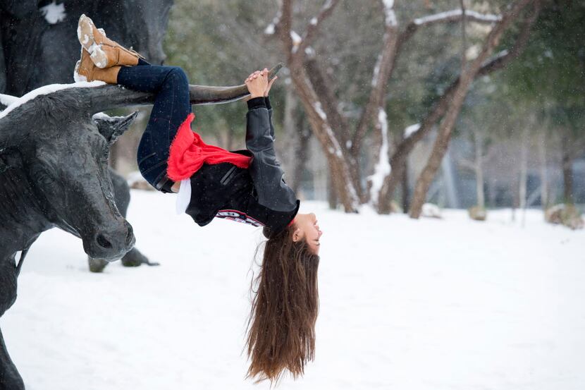 Fabi Gutierrez, 18, hangs off a longhorn sculpture in Pioneer Plaza Friday, February 27,...