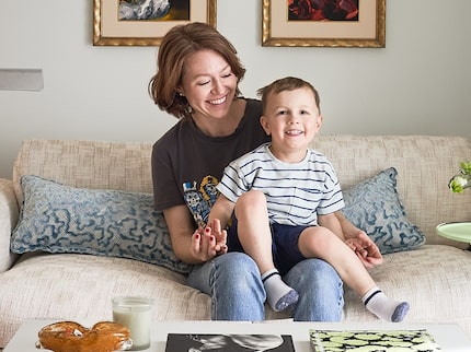 Woman sitting on a white sofa in a living room with a little boy