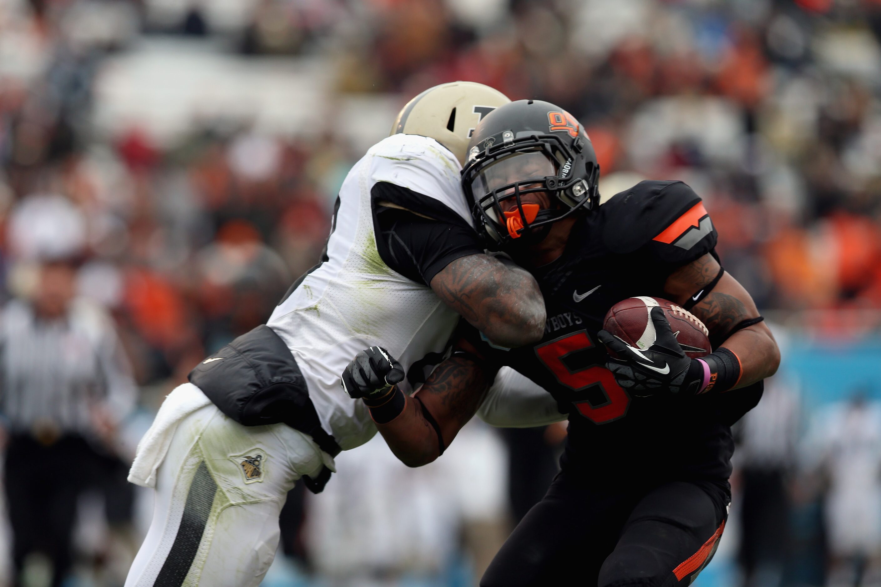 Josh Stewart (5) of the Oklahoma State Cowboys is tackled by Josh Johnson (28) of the Purdue...