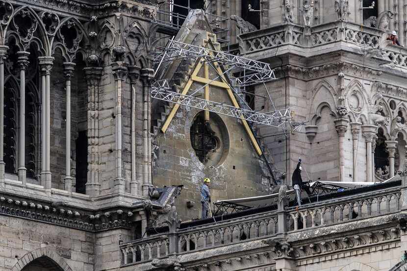 Workers install protective tarps on the roof of  Notre Dame cathedral in Paris on April 23,...