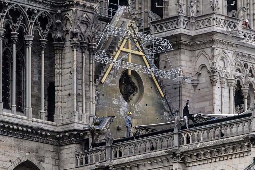 Workers install protective tarps on the roof of  Notre Dame cathedral in Paris on April 23,...