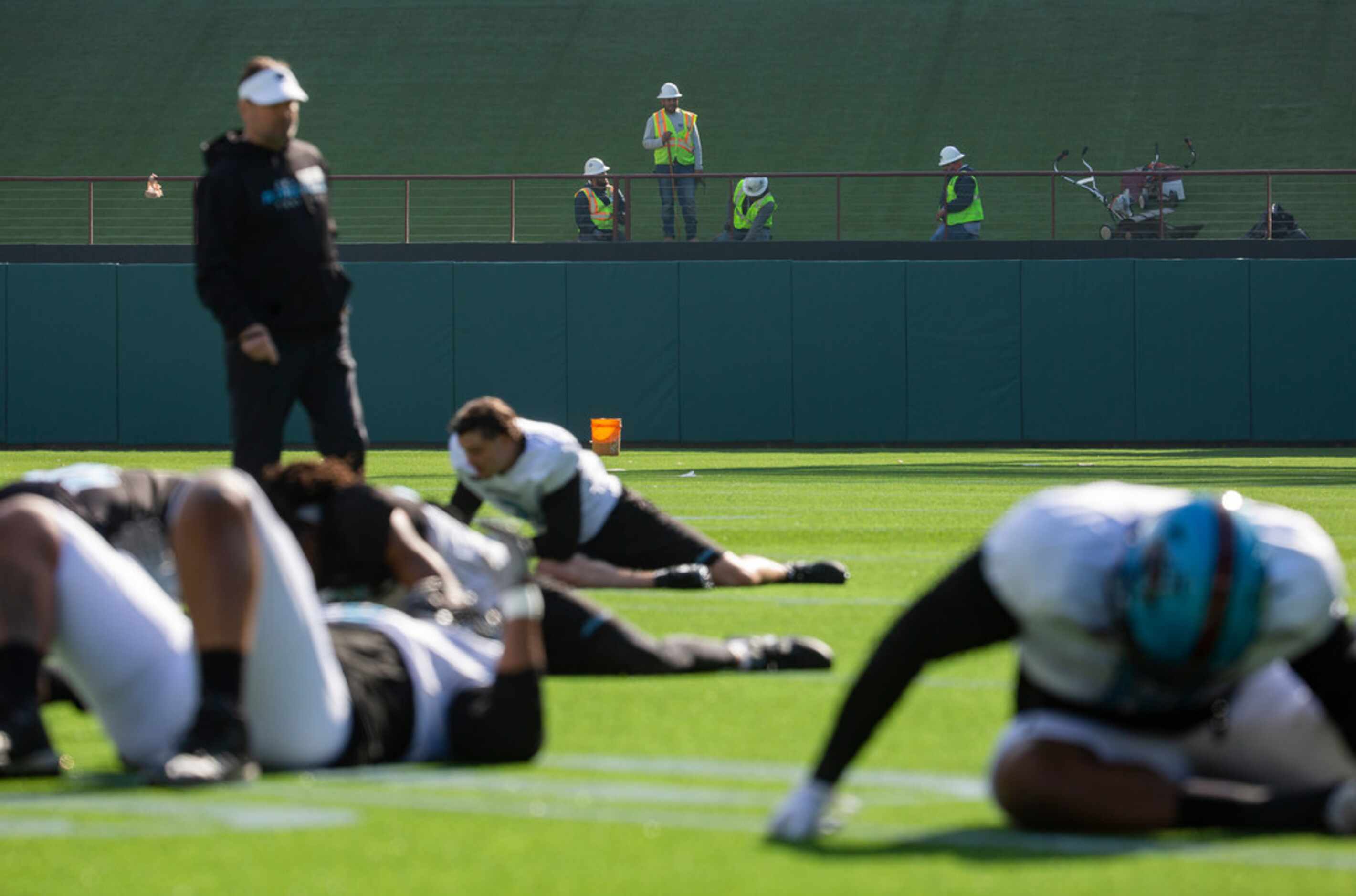 The Dallas Renegades stretch before practice while construction continues at Globe Life Park...