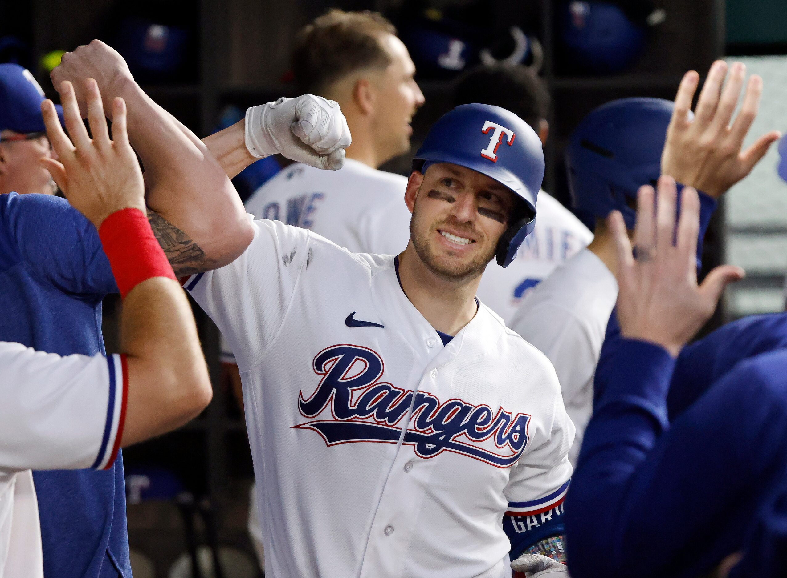 Texas Rangers batter Mitch Garver (18) is congratulated by teammates in the dugout after...