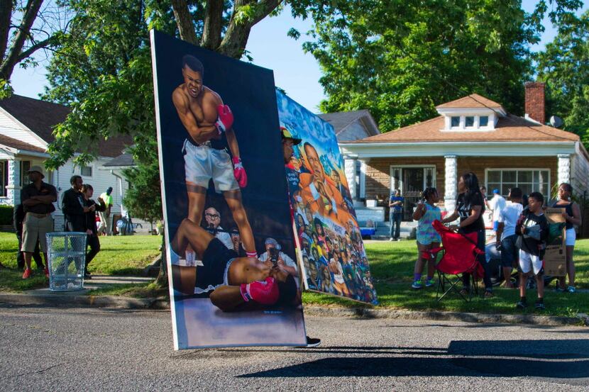 A man walks down the street with a huge painting of boxing legend Muhammad Ali outside his...