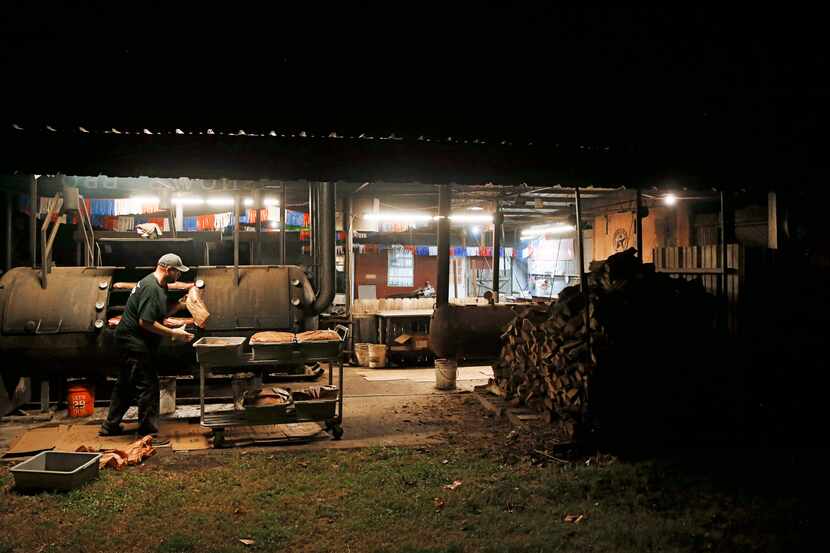 Clay Cowgill works on putting the briskets on the smoker around 10 p.m. at Snow's BBQ in...