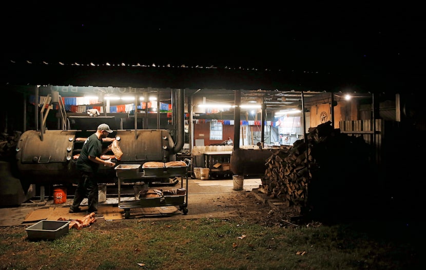 Clay Cowgill works on putting the briskets on the smoker around 10 p.m. at Snow's BBQ in...