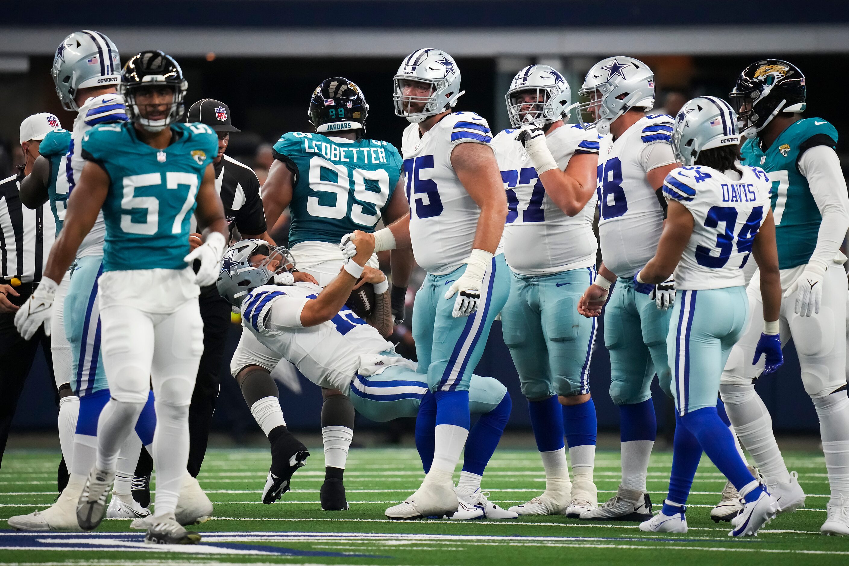 Dallas Cowboys quarterback Will Grier (15) gets a hand up from offensive lineman Josh Ball...