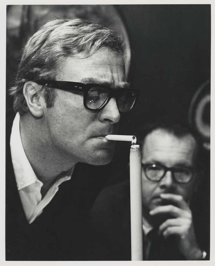 Actor Michael Caine lights a cigarette using a candle, circa 1970s. The photo is included in...