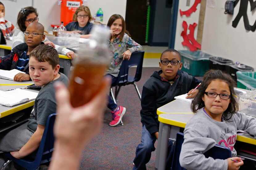 
Carolyn Tackett holds up a bottle of dirty water in front of her class during the water...