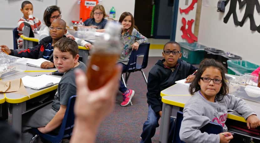 
Carolyn Tackett holds up a bottle of dirty water in front of her class during the water...