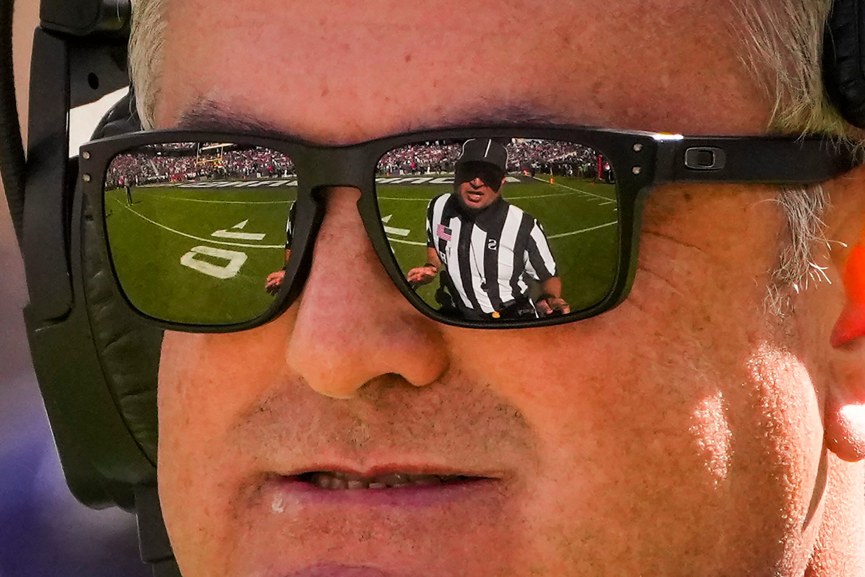 Head linesman Matt Burks is reflected in his glasses as TCU head coach Sonny Dykes ...